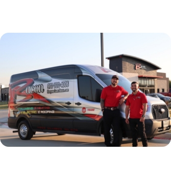 Two technicians in red Bacon Plumbing Heating Air Electric shirts stand confidently in front of a branded service van with the company building in the background.